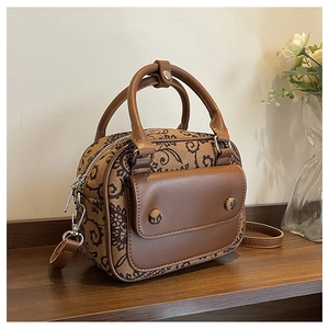 Retro paisley fabric handbag with brown leather trim on a vintage wooden table detail