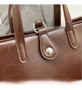 Detail of glossy brown leather bag showing fine stitching and silver metal hardware