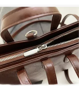 Close-up of smooth silver zipper and D-ring on dark brown leather bucket bag