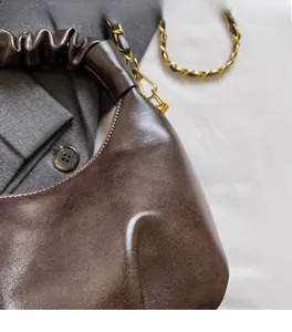 Detail of soft brown pleated Hobo bag with vintage leather texture and gold chain strap