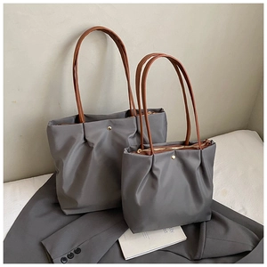 Detail of gray nylon tote bags with leather handles and gold zippers on a suit background