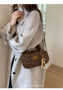 Détail du sac à main léopard avec breloque en perles de bois sur manteau gris