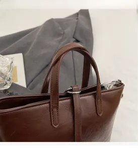 Detailed macro view of the dark brown leather handle and silver metal hardware of the bucket bag