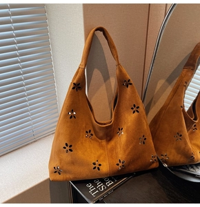 Gros plan du sac en daim caramel avec motifs de fleurs découpées et texture douce