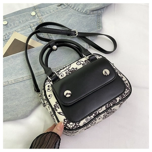 Detail shot of vintage black floral handbag on denim and white textured fabric