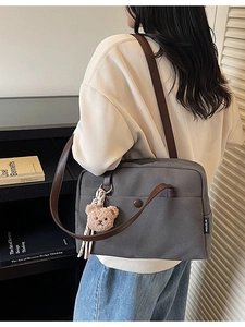 Minimalist dark grey canvas tote bag with leather straps and bear charm shown on shoulder
