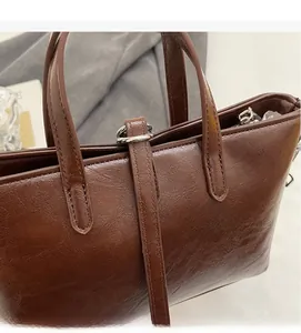 Detailed view of dark brown oil-wax leather texture and metal buckles on a tote handbag