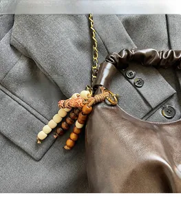 Detail of dark brown pleated handbag with golden chain and beaded tassel ornament