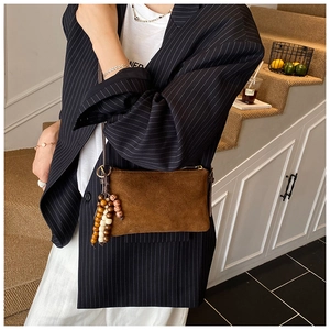 Detalle de bolso bandolera de ante marrón con borla de cuentas de madera estilo étnico