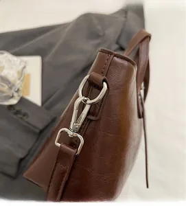 Close-up of the silver metal swivel hook and leather texture on a brown bucket bag