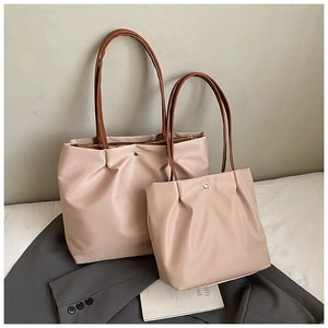 Detail of light beige tote bags with brown leather handles on grey blazer and book