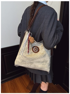 Détail du grand sac cabas en toile avec lanières brunes et pendentif ours sur modèle