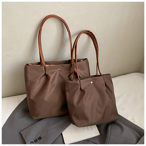 Detail of premium large brown tote bag set placed on a grey blazer for a professional look