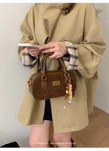 Gros plan d'un sac à main marron en cuir et daim avec charms en perles de bois colorées
