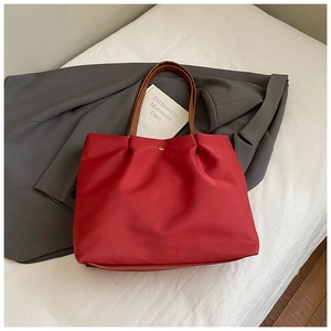 Top view of red tote bag with brown leather handles and magnetic snap closure detail