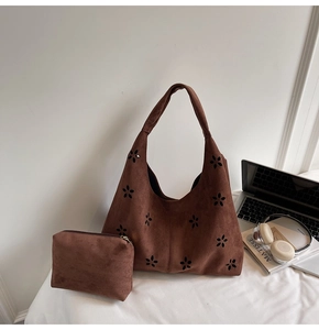Détail du sac cabas en daim marron avec motifs ajourés au laser et pochette assortie