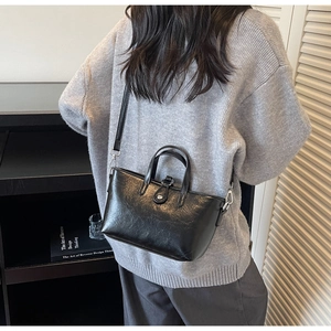 Detailed back view of model wearing a glossy black minimalist faux leather crossbody bag