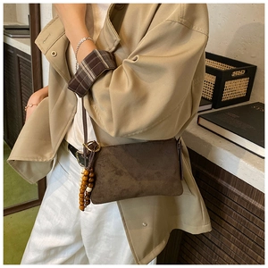 Detalle de bolso de hombro en ante sintético marrón oscuro con borla de cuentas de madera