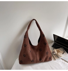 Gros plan d'un sac cabas en daim marron avec motif fleuri ajouré et poignées d'épaule
