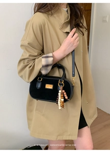 Détail d'un sac bandoulière rétro en daim noir avec pendentif décoratif en perles de bois