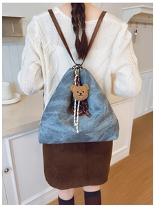Détail d'un sac à dos vintage bleu avec bretelles en cuir et charm ours mignon