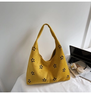 Détail du motif floral ajouré sur le sac hobo en daim jaune vif et chic