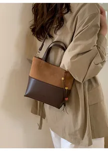 Detailed view of the dual-color bucket bag with shoulder strap and stylish bead charm