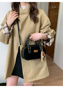 Détail d'un sac à main en daim noir avec gland en perles de bois sur un trench-coat kaki