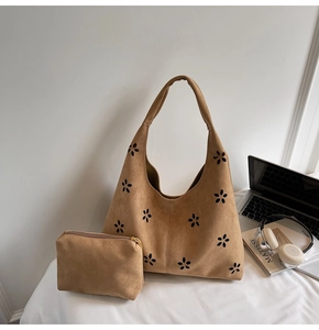Détail d'un sac cabas en daim marron avec motifs floraux découpés au laser et pochette