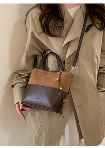 Detail view of two-tone bucket bag with suede texture and a beaded tassel charm