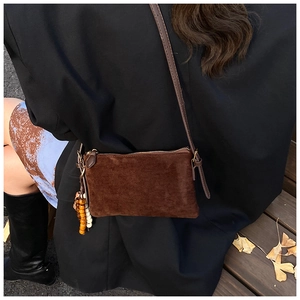 Primer plano de bolso bandolera de ante marrón con cuentas de madera decorativas en otoño