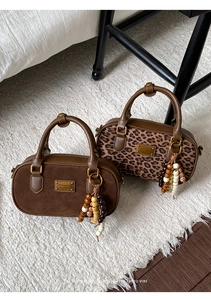 Détail de sacs Boston vintage avec imprimé léopard et pompons perlés sur tapis doux