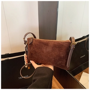 Detalle del mini bolso bandolera de ante marrón café con borla de cuentas étnicas y cremallera