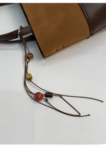 Detail of suede bucket bag featuring ethnic style beaded charm and metal ring hardware