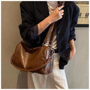 Détail d'un sac Boston vintage en cuir marron avec doubles bandoulières chic