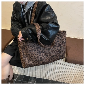 Detail of a large leopard print tote bag with wide shoulder strap on a fashion model