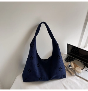 Détails des motifs floraux découpés au laser sur un sac à bandoulière en daim bleu marine