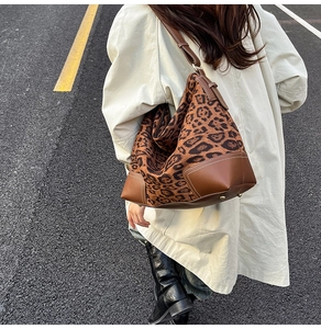 Close-up of leopard print tote featuring brown leather trim and white contrast stitching