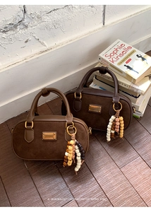 Détail de sacs Boston en daim rétro avec perles décoratives et finitions dorées