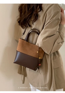 Detail of a dual-material bucket bag with suede splicing and a wooden bead tassel charm