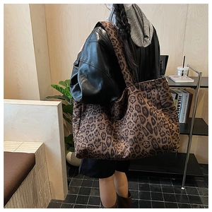 Leopard print tote bag detail showing wide shoulder strap on a model wearing a leather jacket