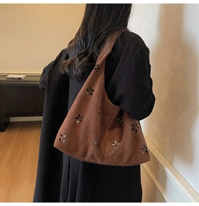 Détail de motifs floraux découpés au laser sur un sac bandoulière en daim marron