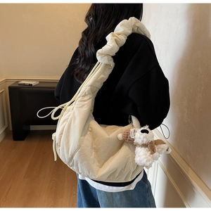 Detailed view of cream ruched cloud bag with cute puppy pendant and wavy shoulder strap