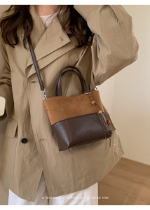Close-up of a retro patchwork bucket bag with tassels on a beige trench coat