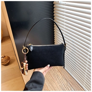 Detalle del bolso de hombro negro mate con cuentas de madera y cremallera dorada