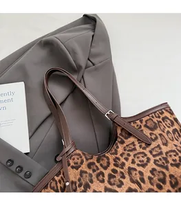 Detail of leopard print fabric texture and brown leather strap with metal buckle