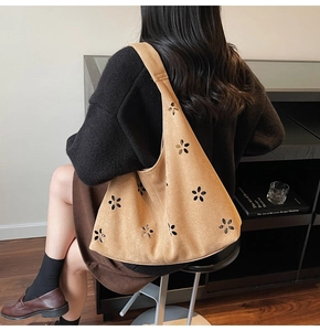 Détail du sac cabas en daim marron avec des motifs floraux découpés au laser