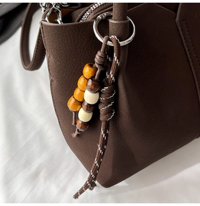 Detailed close-up of dark brown leather bucket bag with ethnic beaded tassel and silver ring