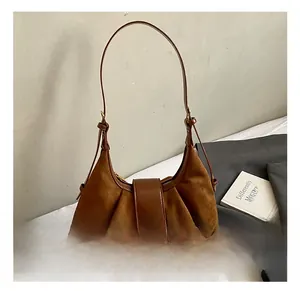 Détail du sac en daim marron avec boucle métallique dorée et design plissé vintage élégant