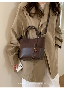 Detail of dark brown leather bucket bag with wooden bead charm and branding emboss